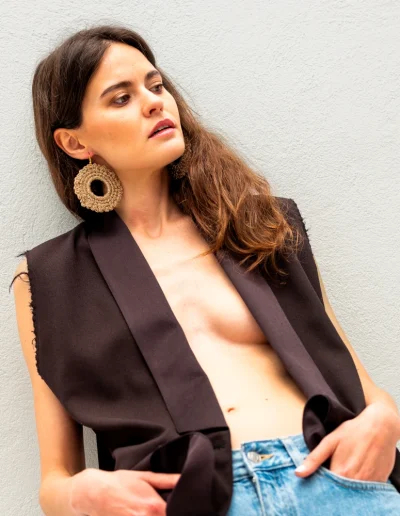 Estilo urbano-bohemio con pendientes circulares dorados BeMeknes: modelo con americana sin mangas y pendientes de crochet artesanal. Joyería textil ligera que contrasta con looks estructurados, ideal para día o noche. Pendientes slow fashion hechos a mano, ligeros y con simbolismo circular.