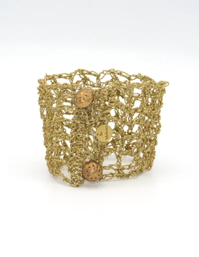Brazalete Tomoe de ganchillo dorado, tejido a mano con hilo metalizado. Inspirado en las valientes guerreras japonesas, combina tradición y elegancia en una pieza artesanal única. Joyería ligera y sostenible con nombre propio.