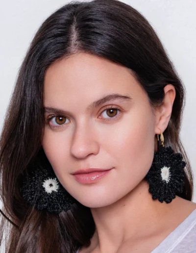 Pendientes Magalí de ganchillo negro y blanco - Inspirados en margaritas. Modelo luciendo estos pendientes artesanales tejidos a mano, con centro blanco y pétalos negros. Complementos únicos de moda slow fashion.