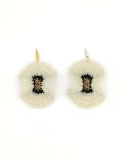 Detalle de pendientes blancos y dorados hechos a mano