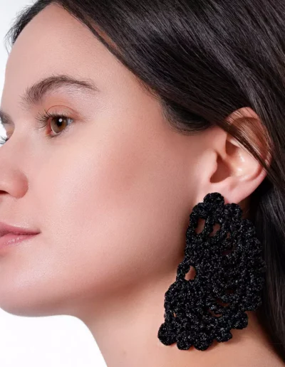 Chica luciendo pendientes Eclipse Negro: Luna eclipsada tejida a crochet con hilo negro. Pieza artesanal que brilla con estilo bohemio y celestial.