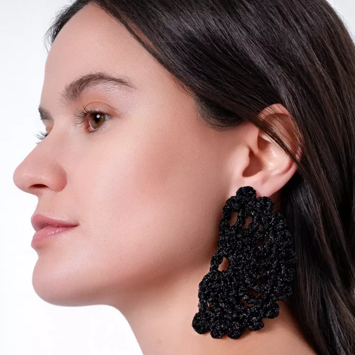 Chica luciendo pendientes Eclipse Negro: Luna eclipsada tejida a crochet con hilo negro. Pieza artesanal que brilla con estilo bohemio y celestial.