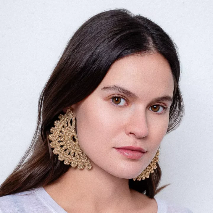 Modelo luciendo pendientes Eclipse Oro: sol eclipsado tejido a crochet con hilo dorado. Pieza artesanal que brilla con estilo bohemio y celestial.