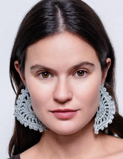 Chica luciendo pendientes Eclipse Plata: luna eclipsada tejida a crochet con hilo dorado. Pieza artesanal que brilla con estilo bohemio y celestial.