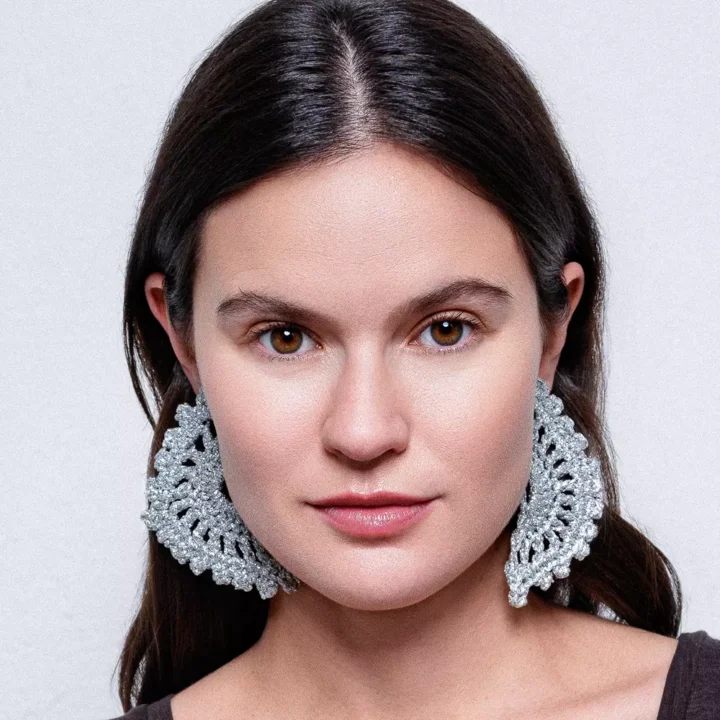 Chica luciendo pendientes Eclipse Plata: luna eclipsada tejida a crochet con hilo dorado. Pieza artesanal que brilla con estilo bohemio y celestial.
