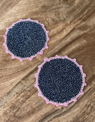 Posavasos Redondo Azul Marino tejidos a mano en azul marino con ribete rosa.