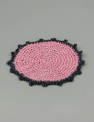 Detalle del posavaso Redondo Rosa artesanal con puntilla azul marino.