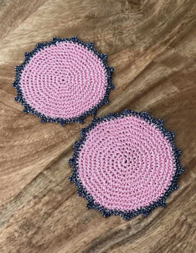 Posavasos Redondo Rosa tejidos a mano en rosa con borde azul marino.