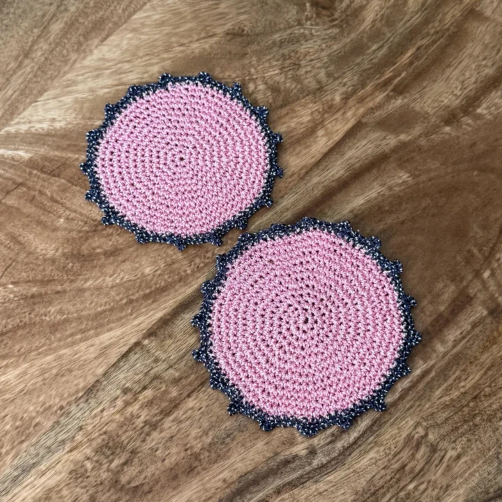 Posavasos Redondo Rosa tejidos a mano en rosa con borde azul marino.