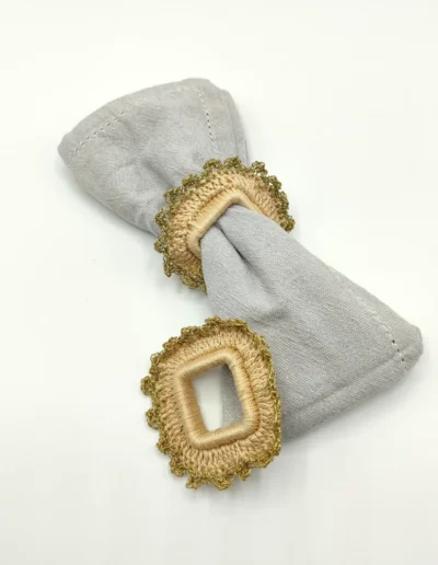 Conjunto de cuatro servilleteros artesanales de forma cuadrada, tejidos a mano en tono natural con ribete en color oro. Un detalle elegante para mesas con alma.