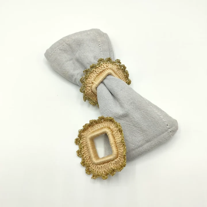 Conjunto de cuatro servilleteros artesanales de forma cuadrada, tejidos a mano en tono natural con ribete en color oro. Un detalle elegante para mesas con alma.