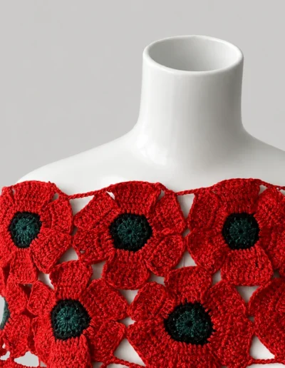 Mañanita artesanal de flores de amapola sobre maniquí blanco